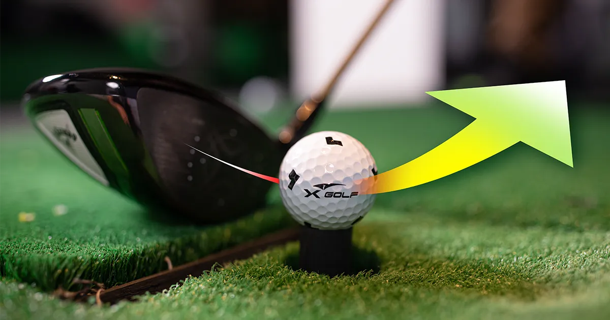 Close-up of a golf club striking an X-Golf ball with a trajectory arrow, visually illustrating what is ball speed in golf and how launch angle affects performance.