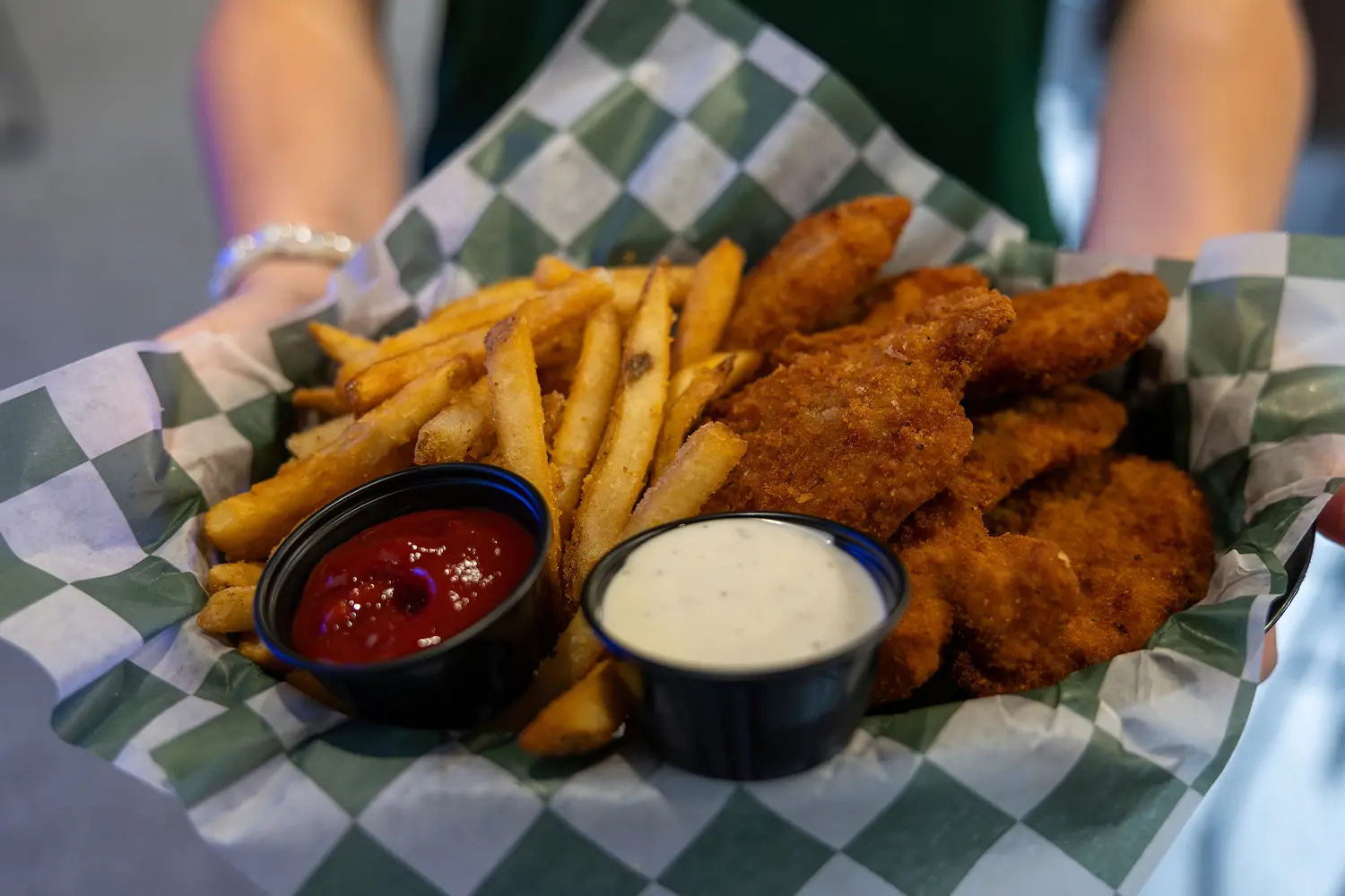 Basket of crispy chicken tenders and fries served with ketchup and ranch dipping sauces.