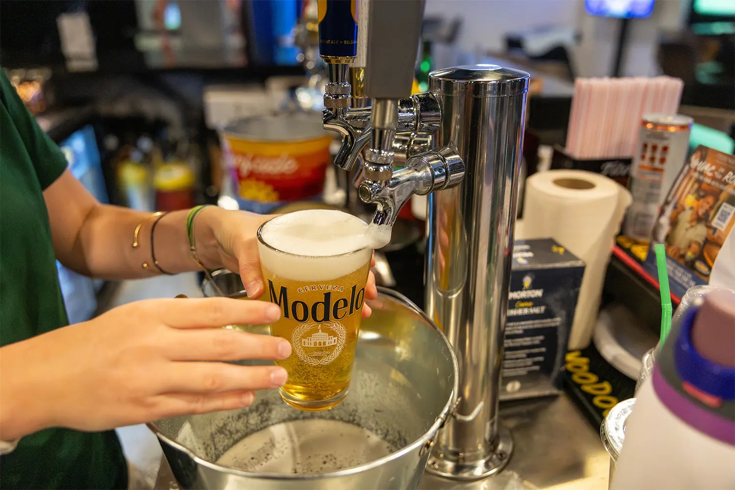 Draft Modelo beer being poured into a pint glass at the bar.